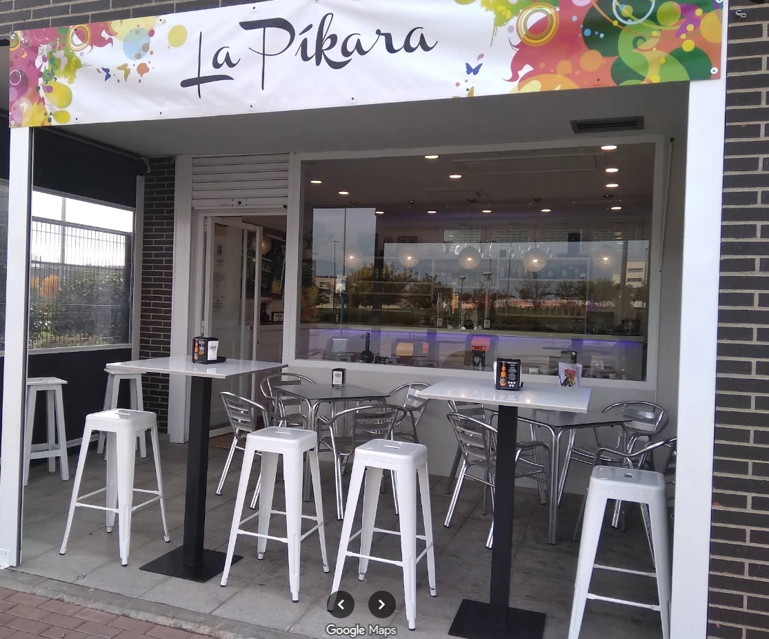 Fachada de La Píkara, con mesas altas, taburetes y su rótulo de colores